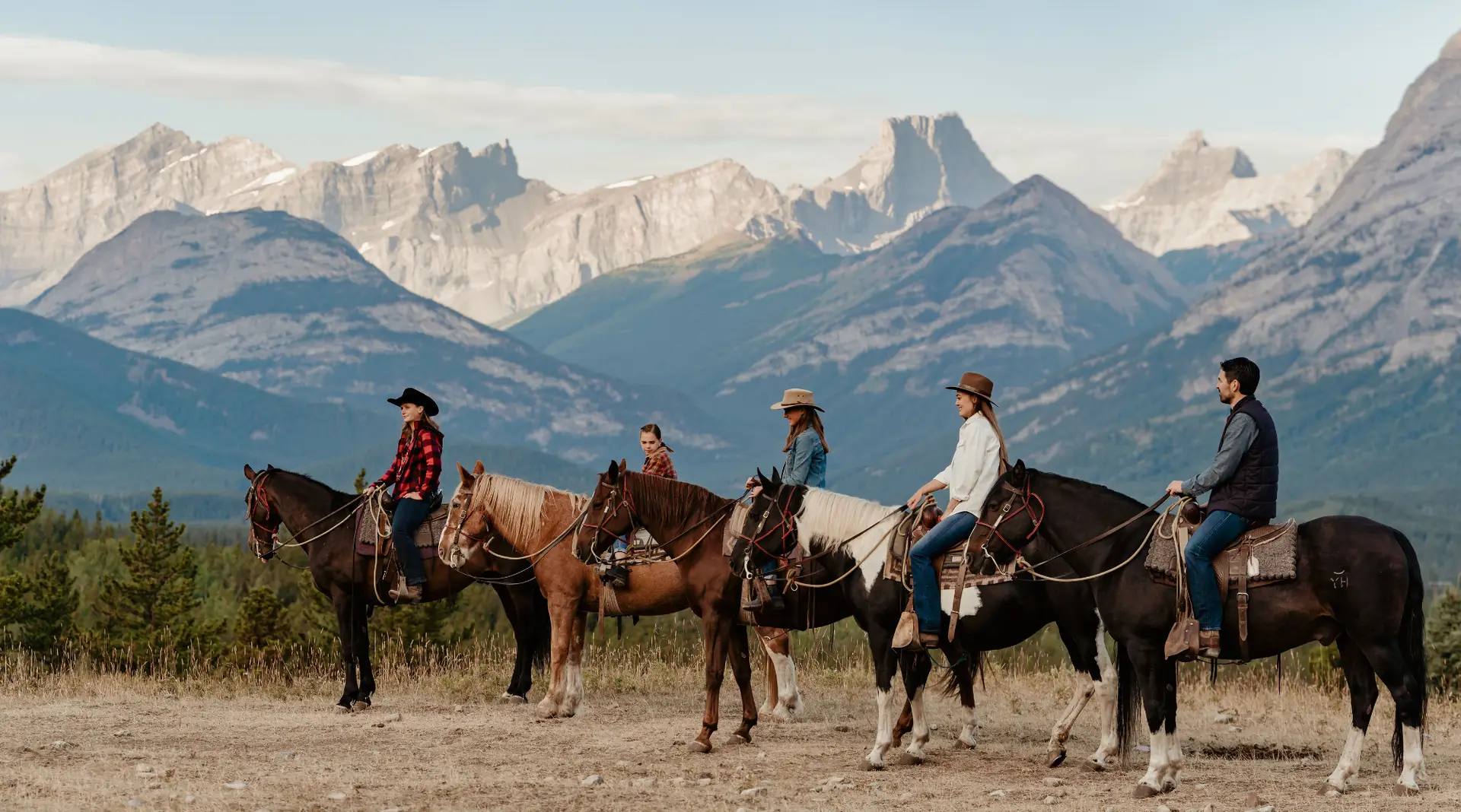 Ranch guests on horseback with mountain backdrop at Boundary Ranch