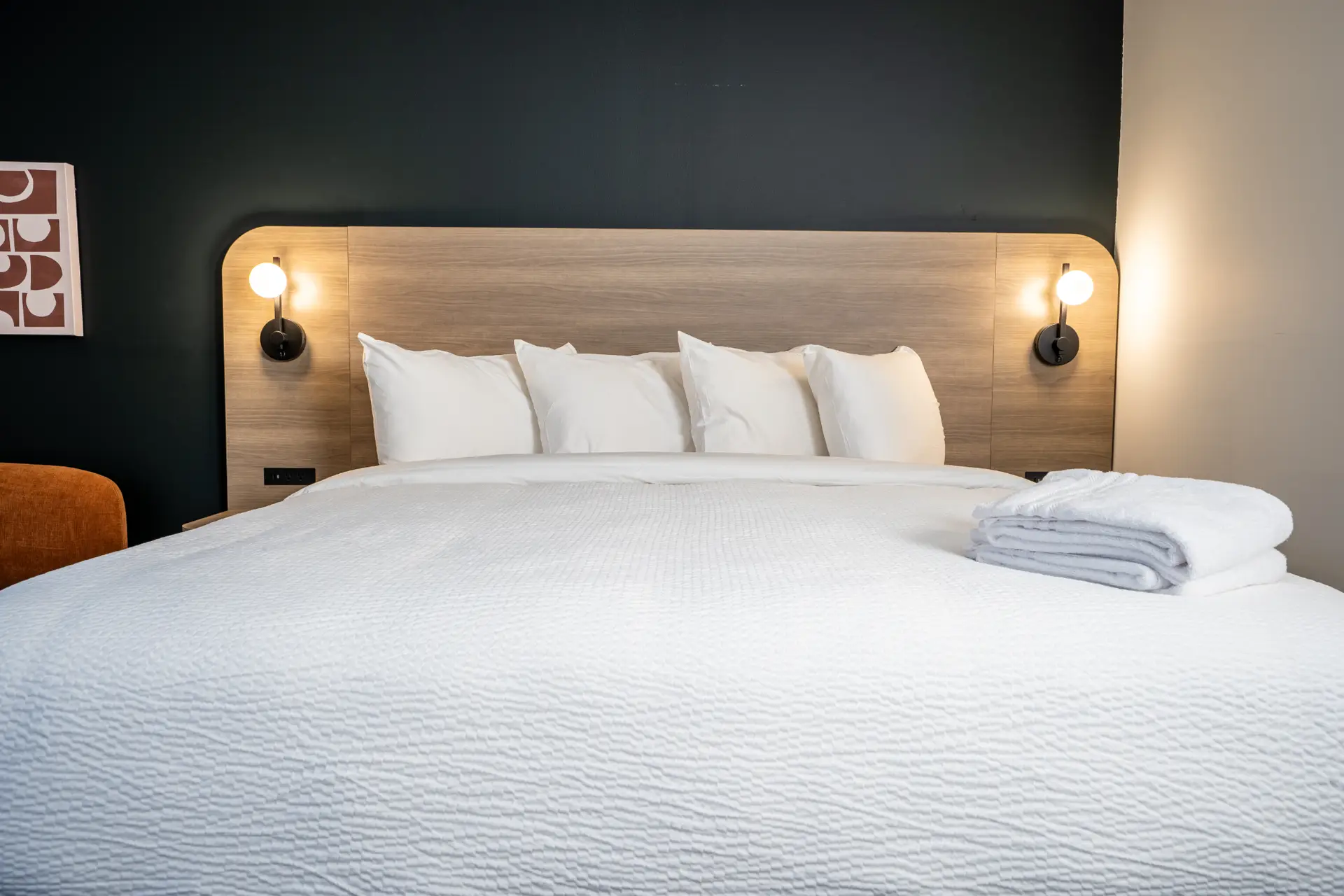 King-size bed with white linens and plush pillows in a modern hotel room