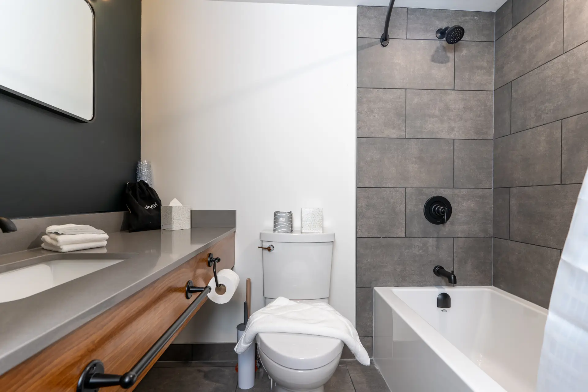 Modern hotel bathroom with king bed, vanity, toilet, and shower