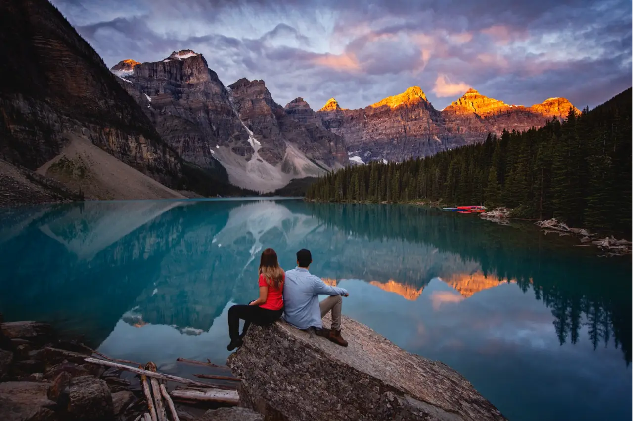 Couple admires Banff's Moraine Lake at sunset, peak perfection