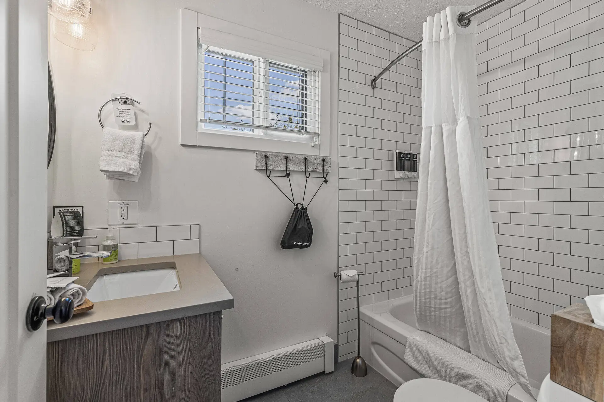 Queen suite bathroom at Basecamp Lamphouse Canmore with shower, tub, and vanity.