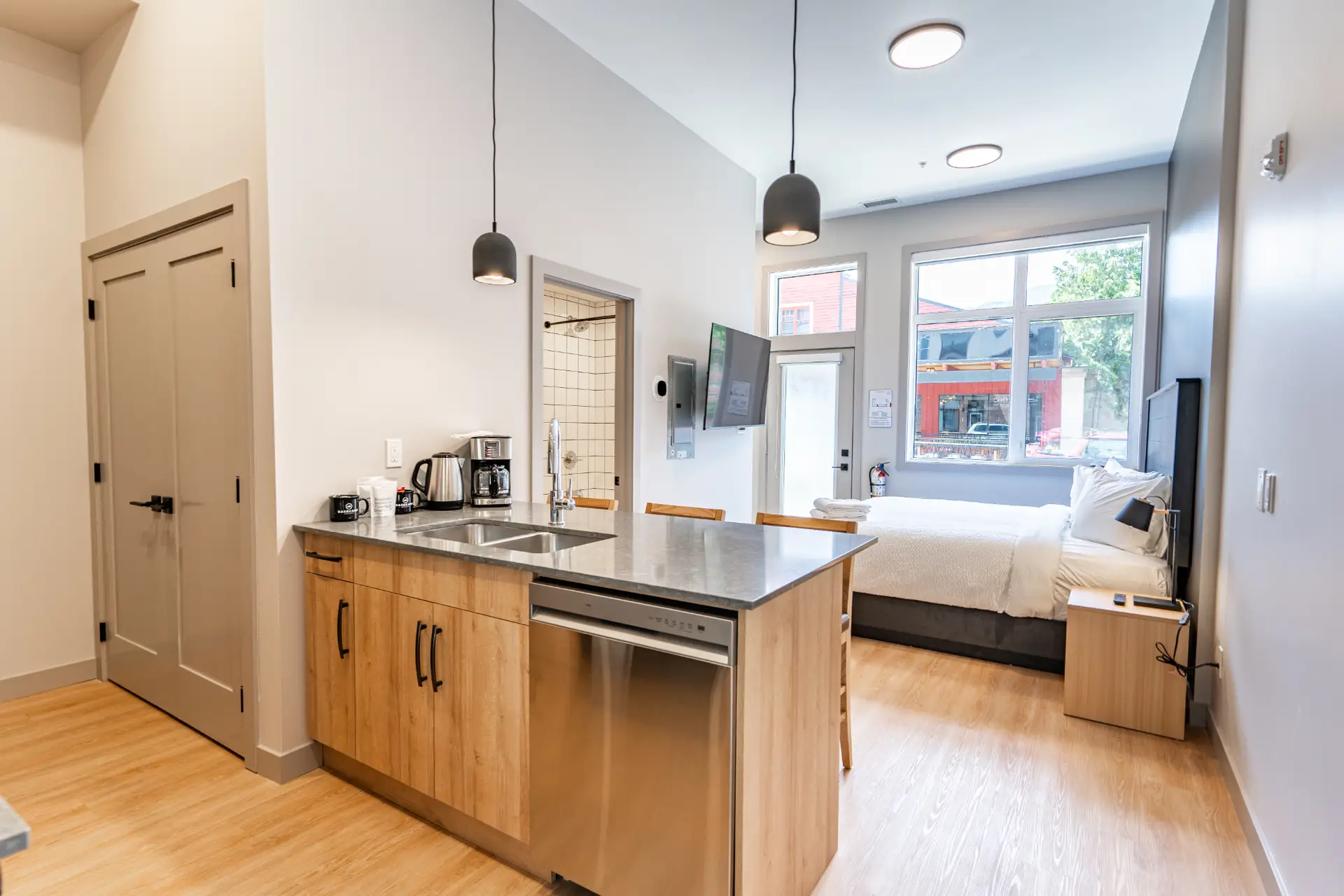 Basecamp Suites Revelstoke micro studio with kitchen, bed, and shower.