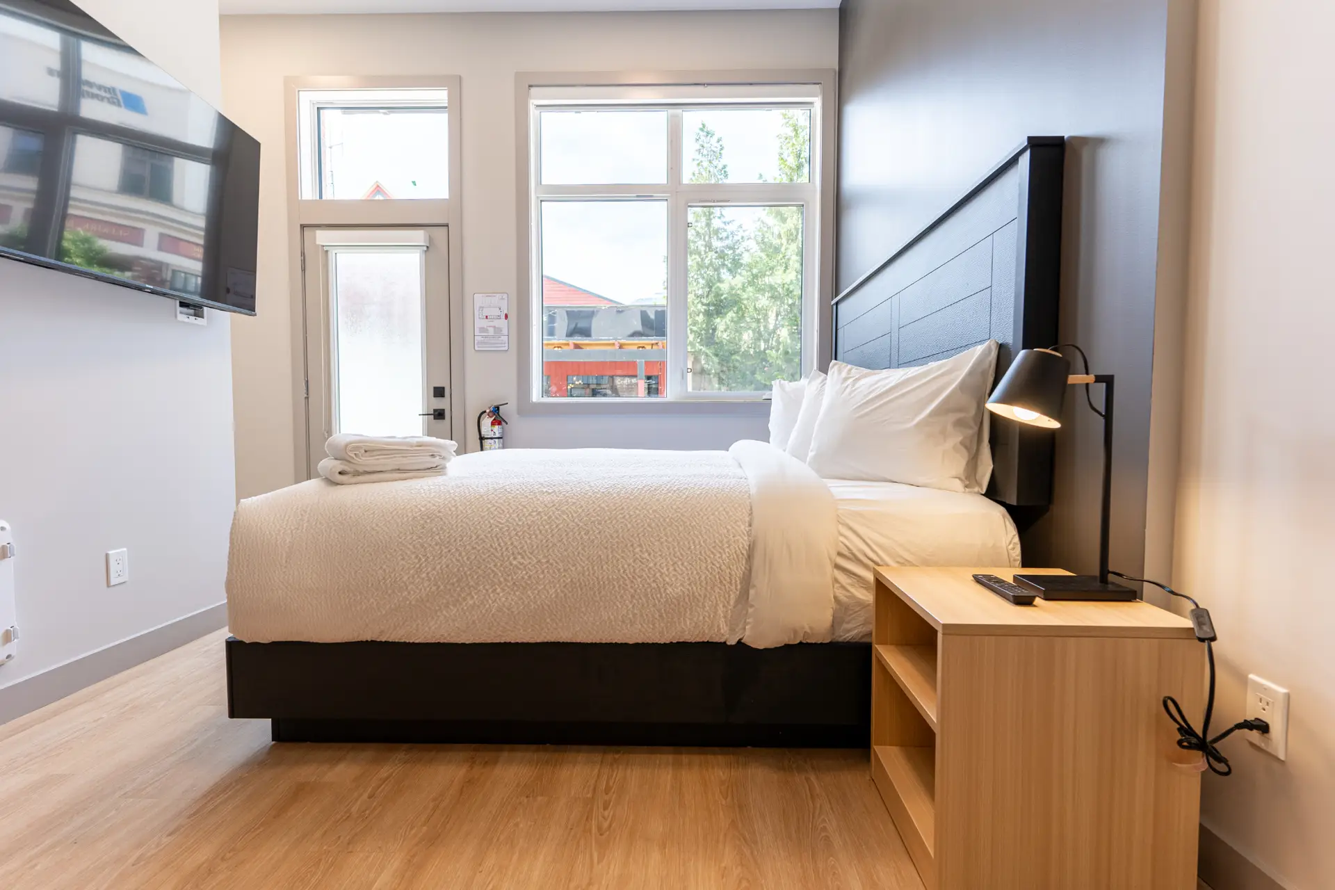 Micro studio at Basecamp Suites Revelstoke with a bed, nightstand, and TV.