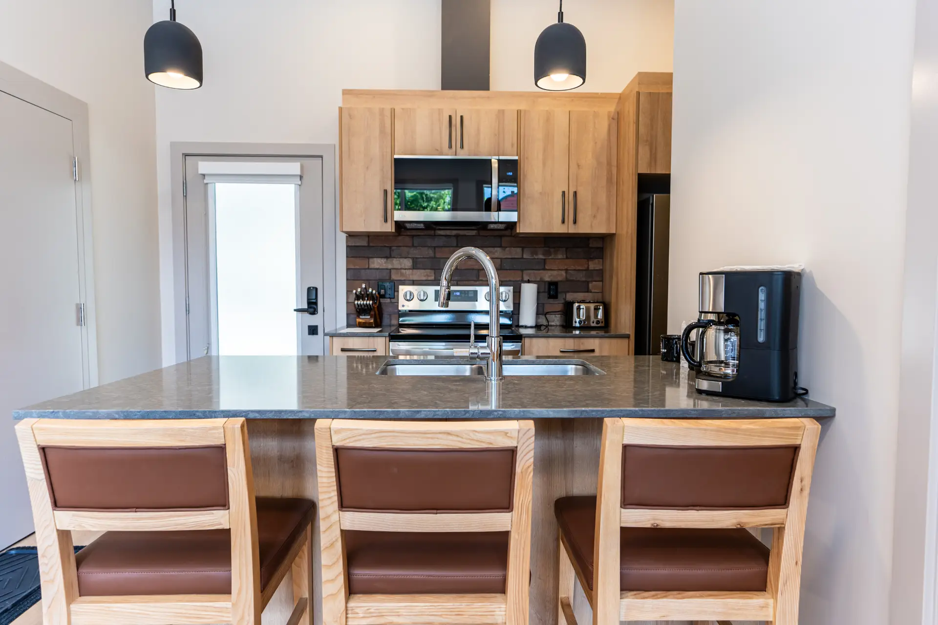 Modern kitchen island with granite countertop and bar stools in a Basecamp Suites micro studio.