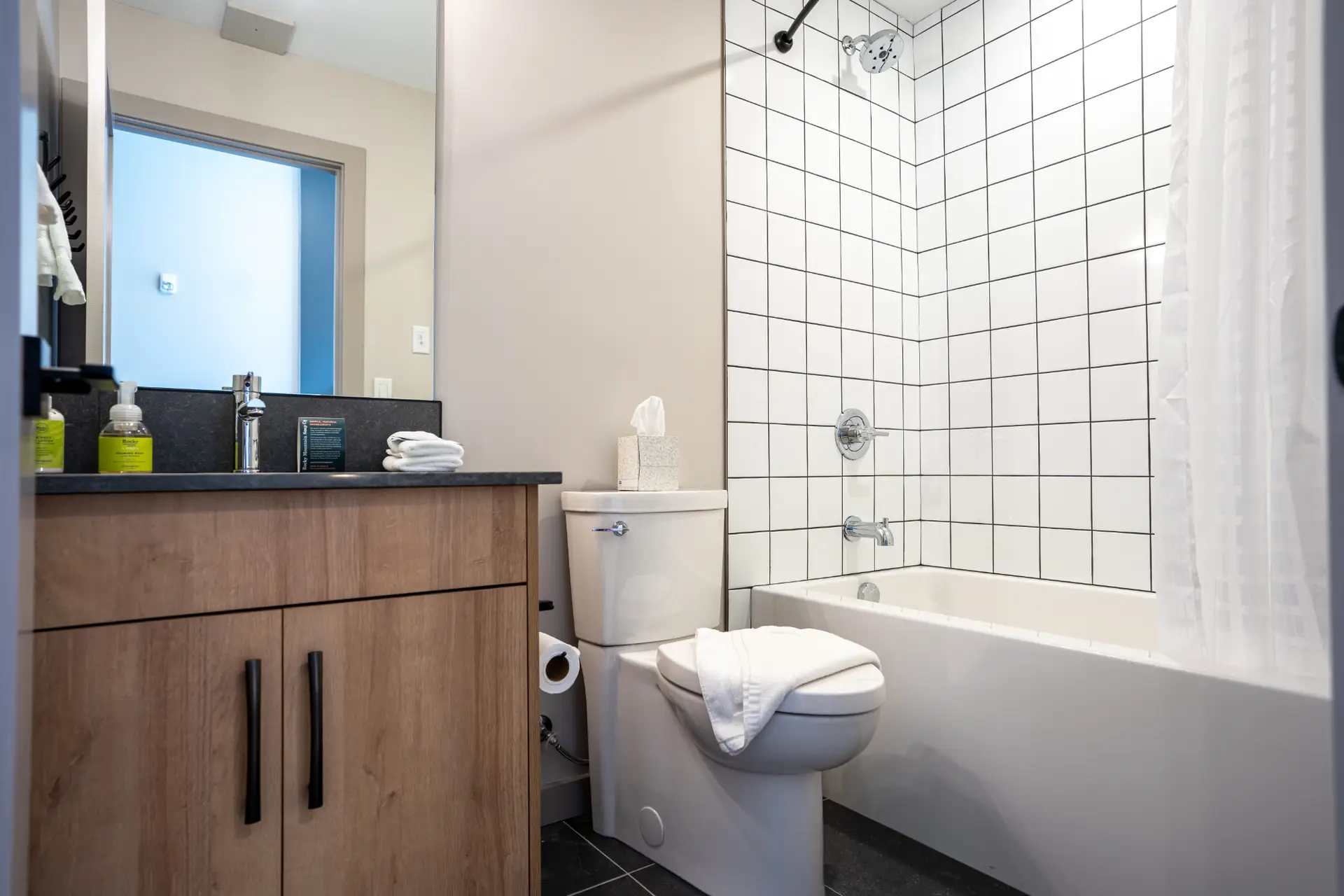 Modern bathroom in Revelstoke micro studio with white subway tile shower and wood vanity.