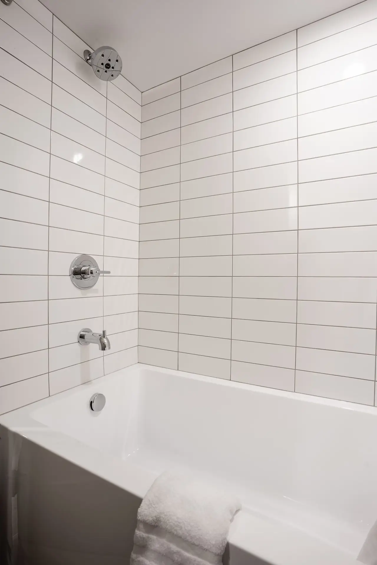 Modern white tiled bathtub and shower in Basecamp Suites Banff one bedroom suite.
