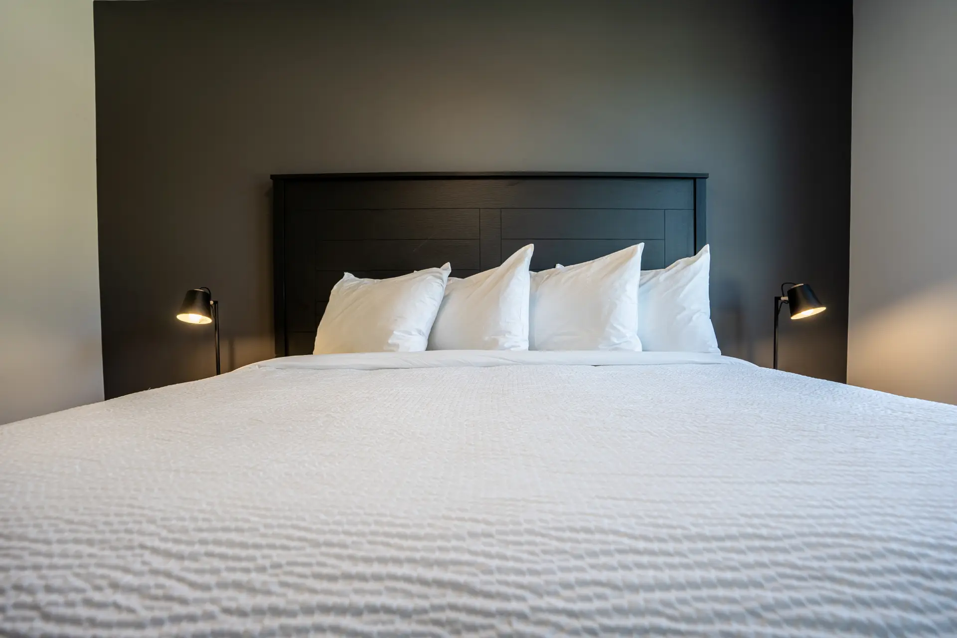 King-size bed with white linens and pillows in a modern hotel room