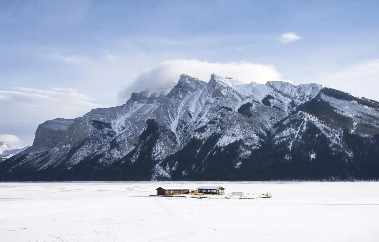 Hidden winter gem: wooden building on frozen Lake Minnewanka, Canadian Rockies