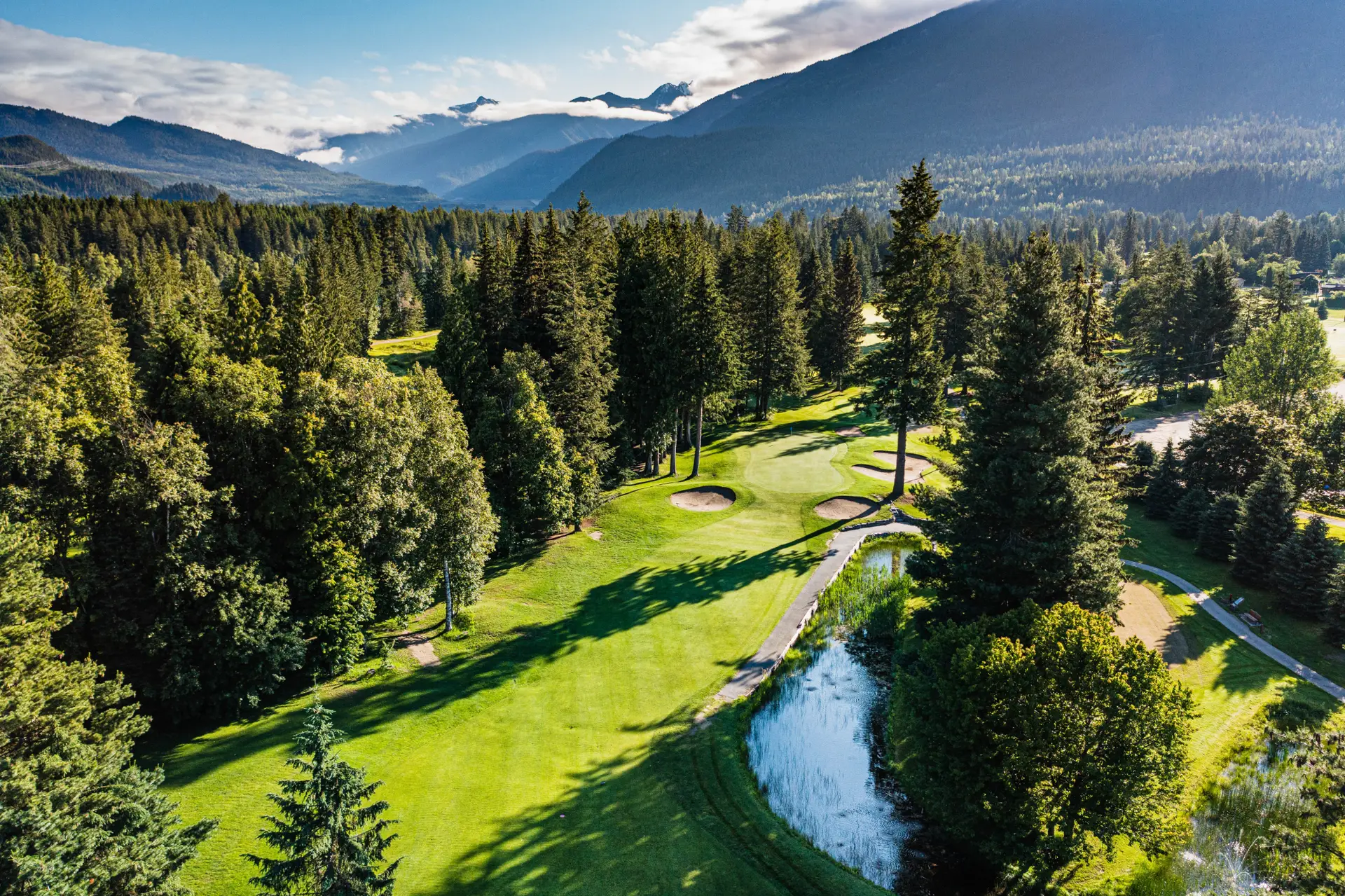 Revelstoke Golf Course with lush fairways, sand traps, and a pond.