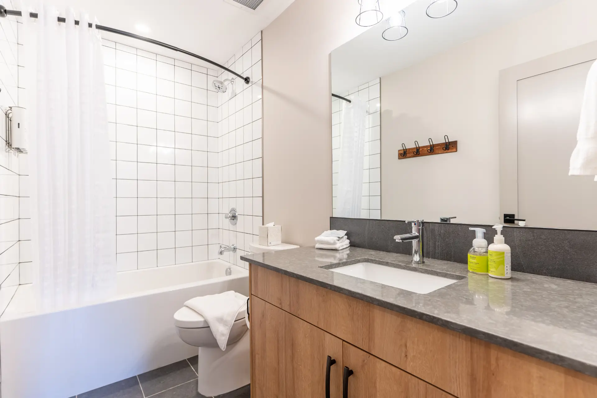 Modern bathroom in Basecamp Suites Revelstoke One Bedroom Suite with white tile shower.