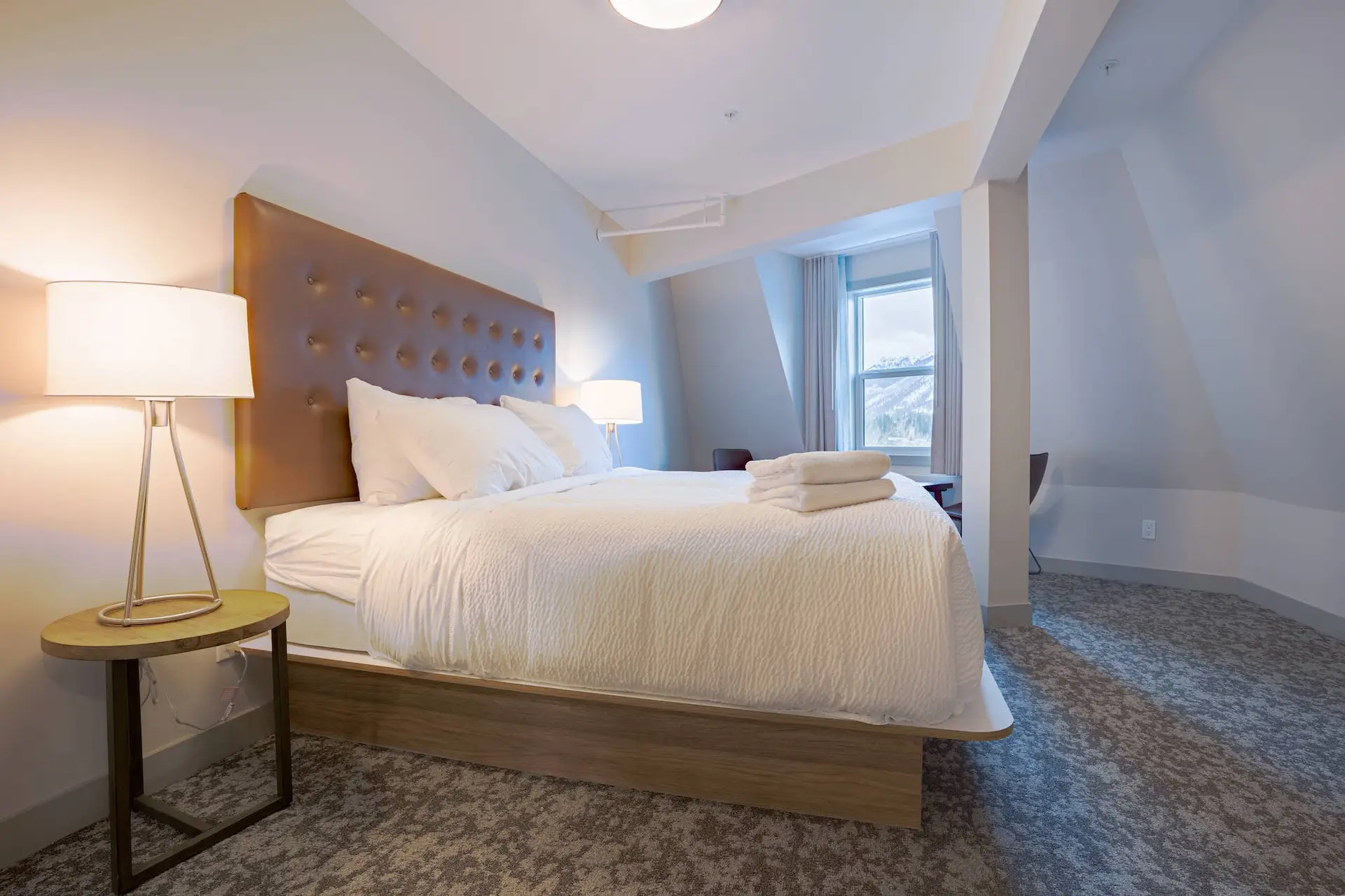 Cozy hotel bedroom with king-size bed, mountain view, and plush carpeting