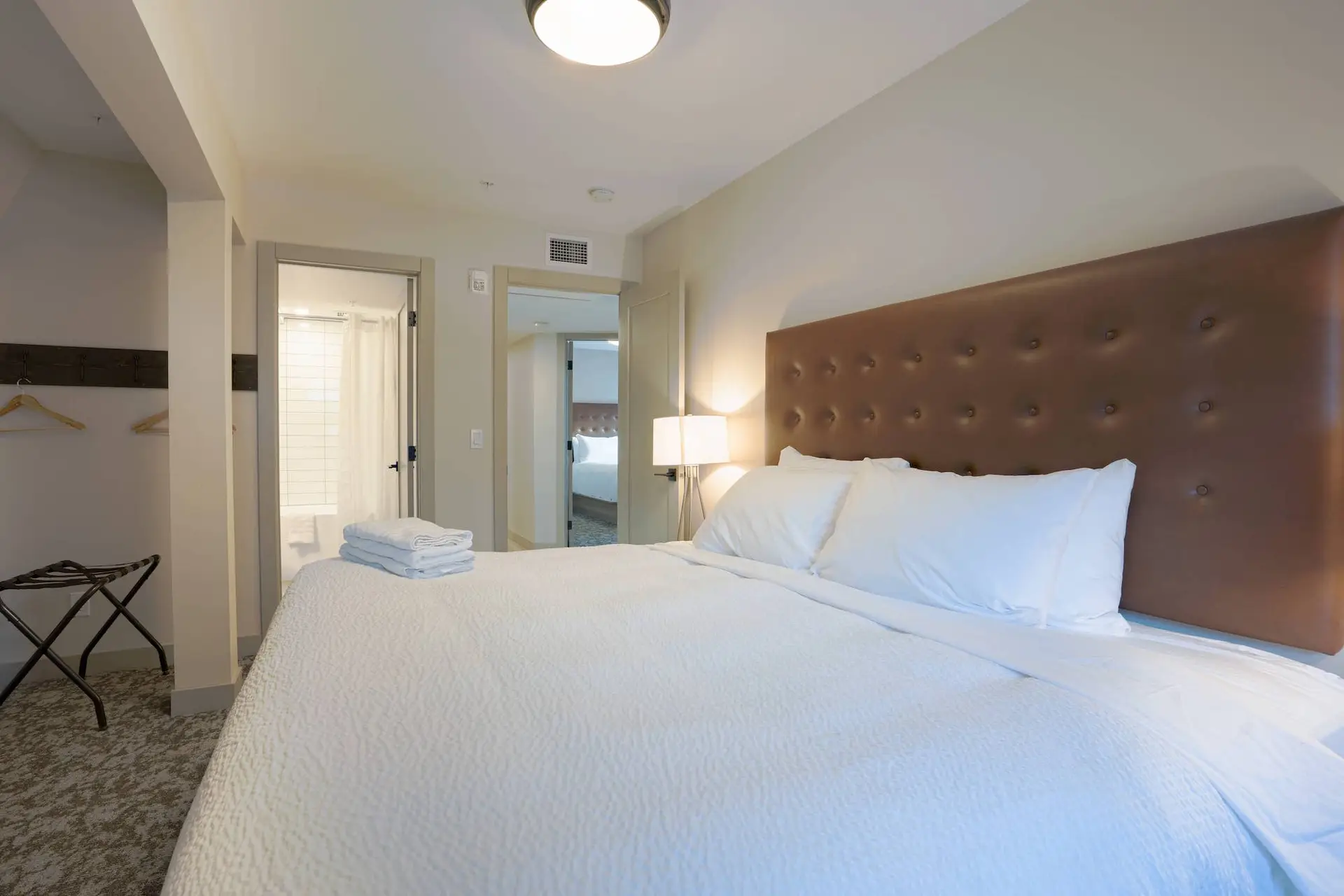Basecamp Suites Banff: King bed in a modern hotel suite with a leather headboard.