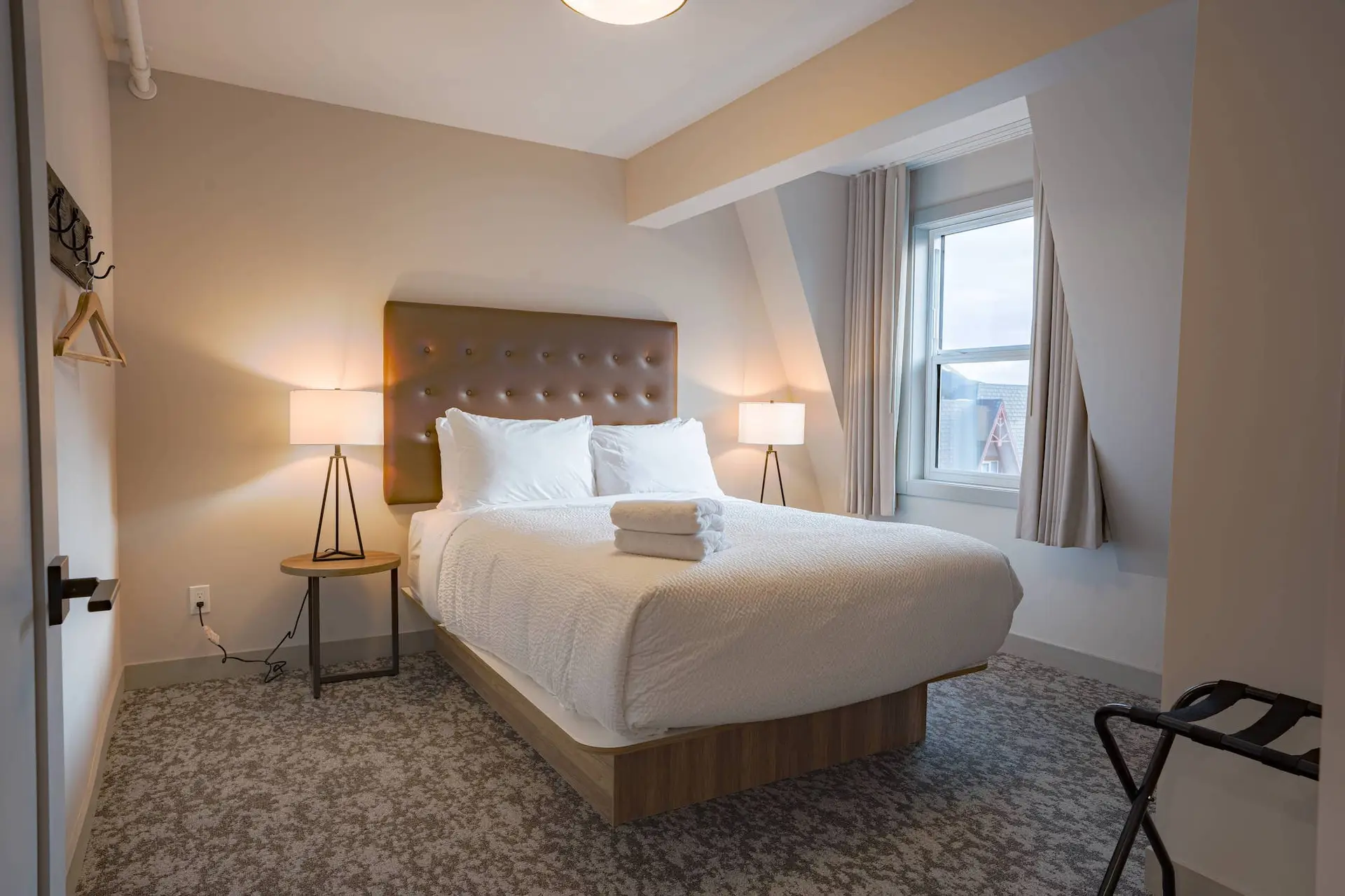 Cozy bedroom with queen bed, plush headboard, and bedside lamps.