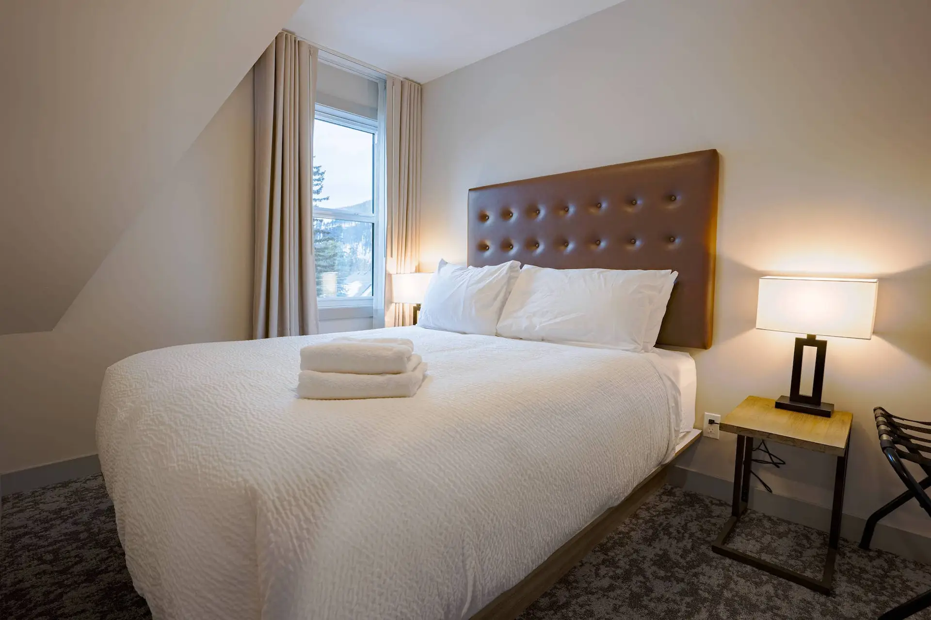 Cozy bedroom in Basecamp Suites Banff Superior Two Bedroom Suite with comfortable bed and window view.