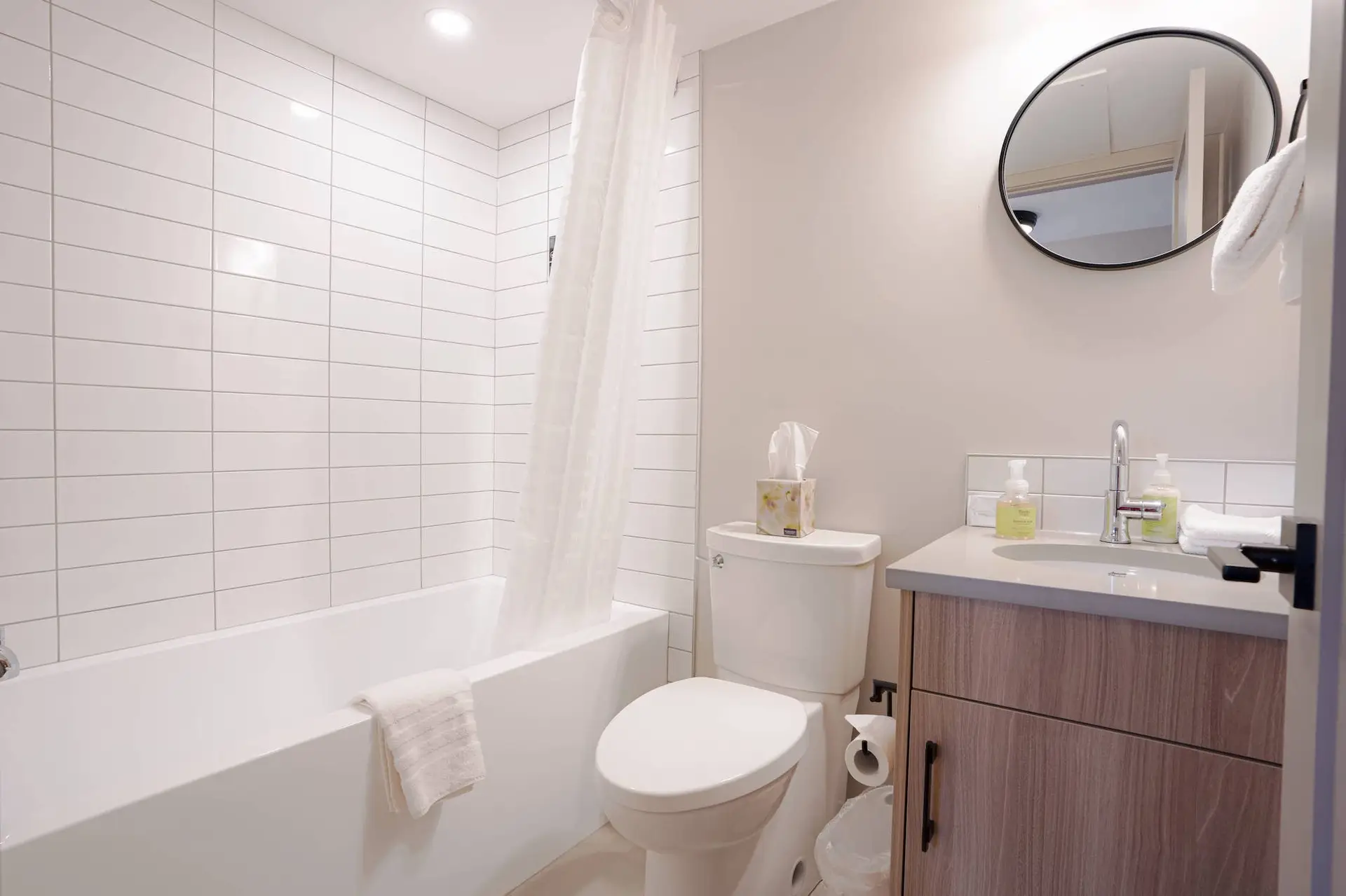 Modern bathroom in Basecamp Suites Banff Superior Two Bedroom Suite with bathtub, toilet, and vanity.