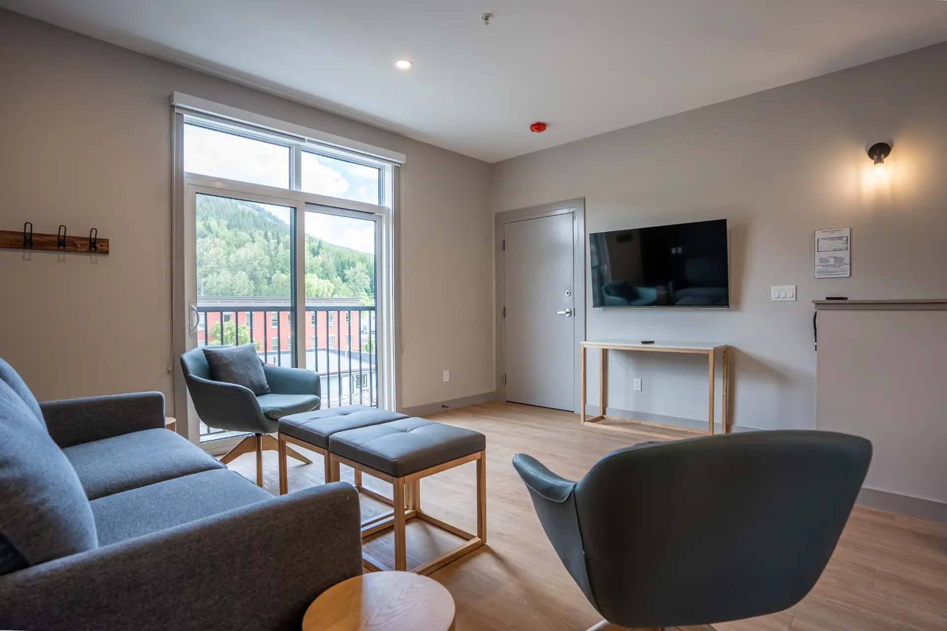 Living room of a two-bedroom suite at Basecamp Suites Revelstoke with a sofa, chairs, and TV.