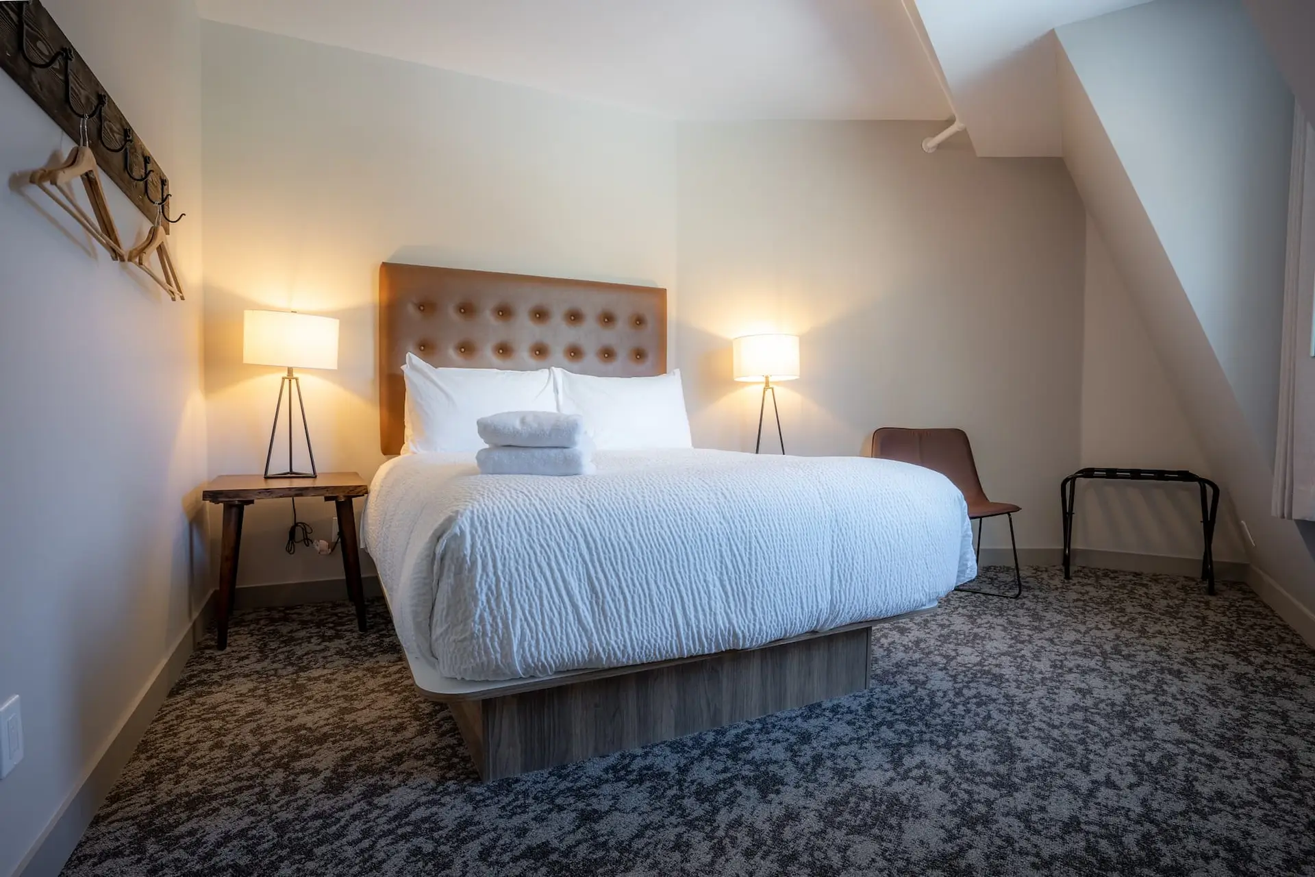 Cozy bedroom in Basecamp Suites Banff with a king bed, bedside lamps, and luggage rack.