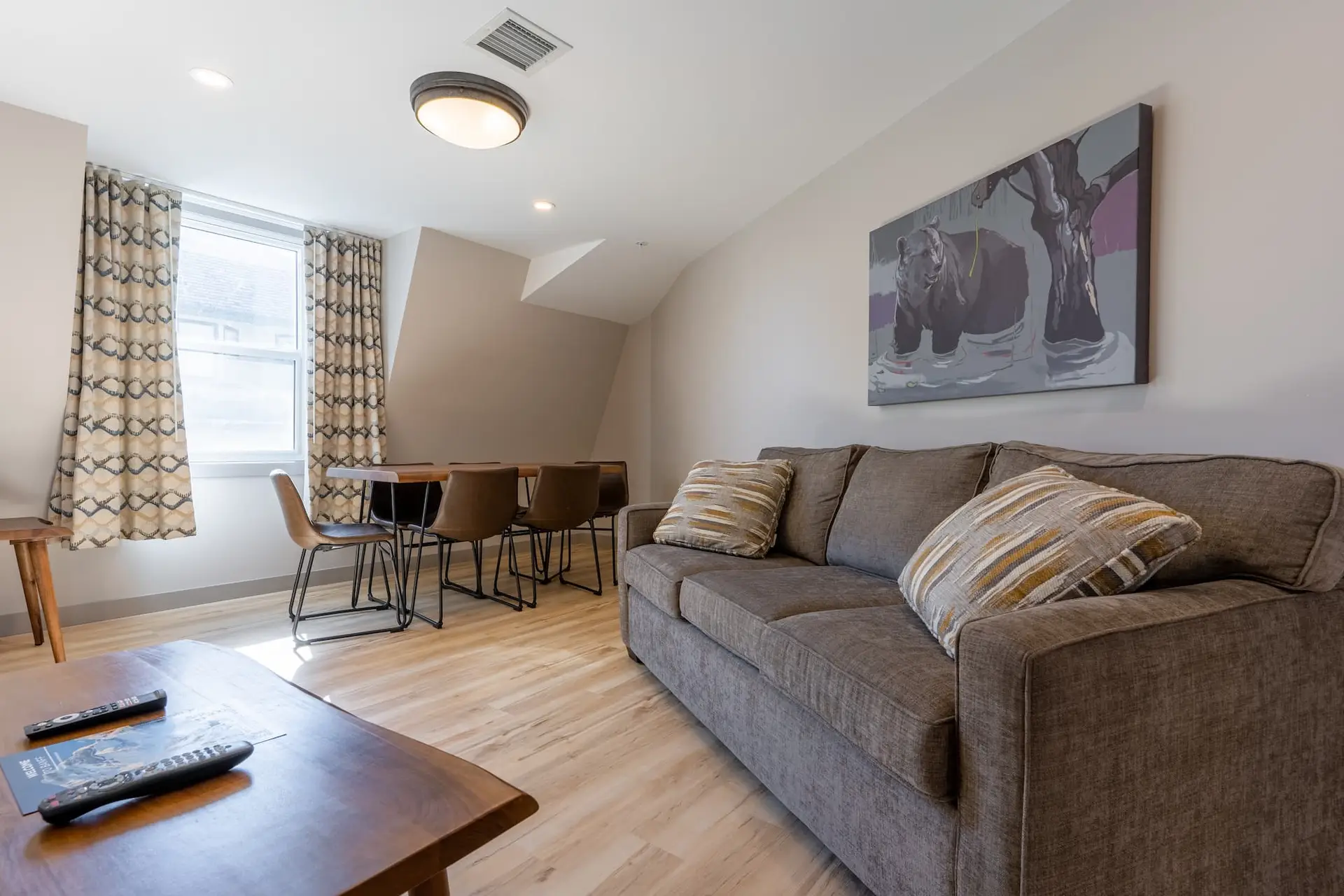Living area of a Basecamp Suites Banff three-bedroom suite with sofa and dining table.