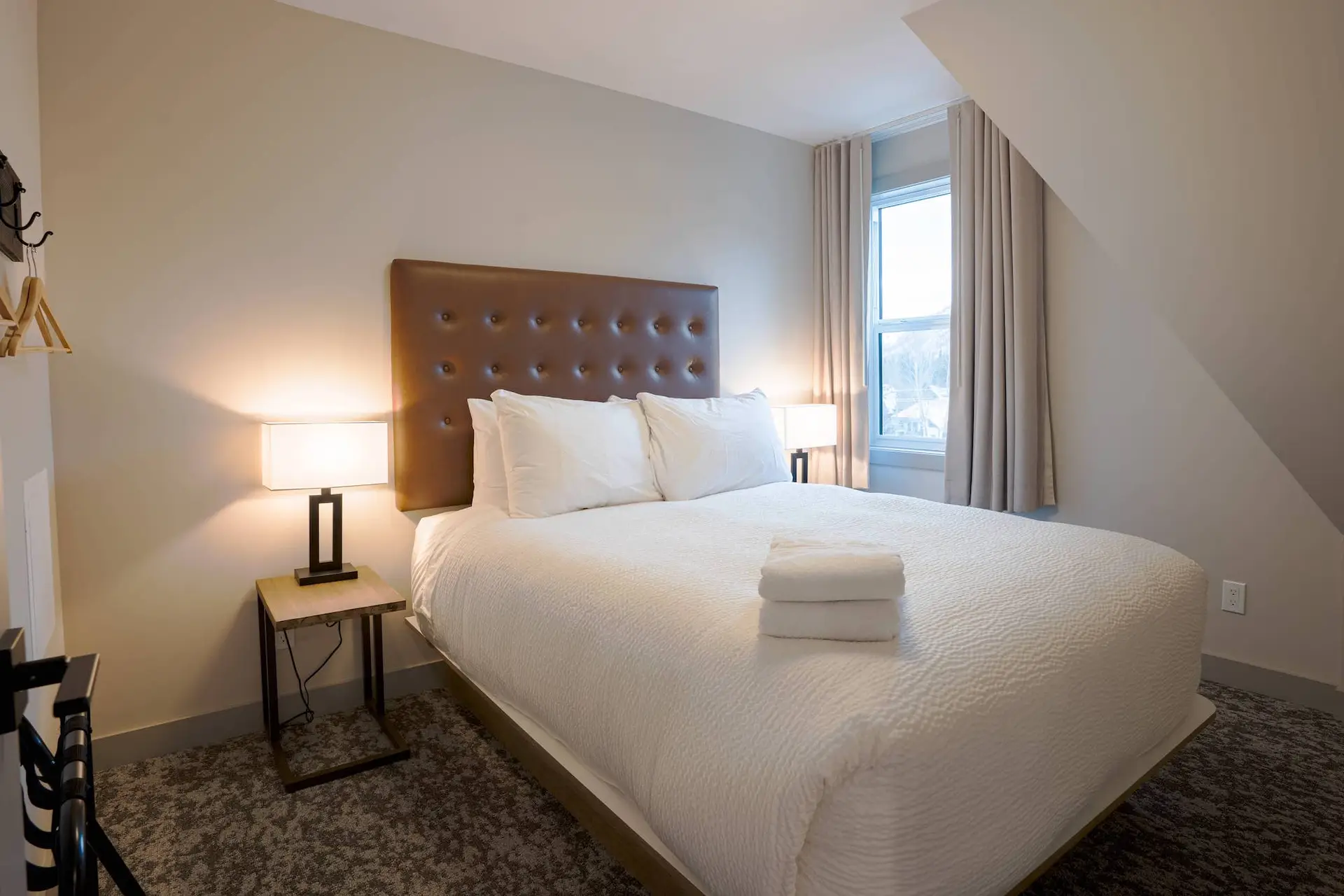 Cozy bedroom in Basecamp Suites Banff Two Bedroom Suite with plush white bedding.