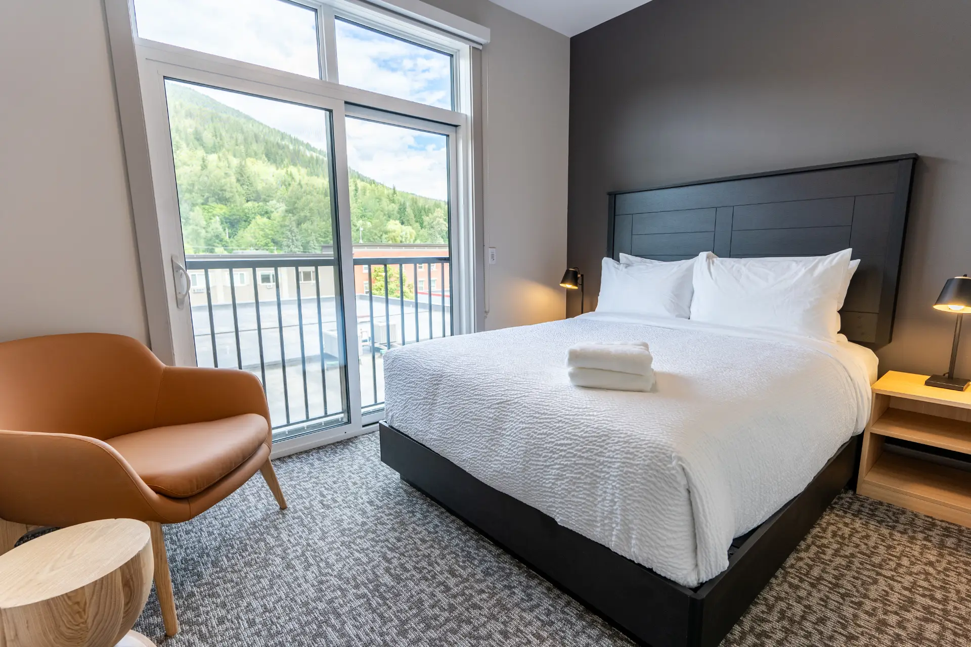 Basecamp Suites Revelstoke two-bedroom suite with king bed, chair, and mountain view.