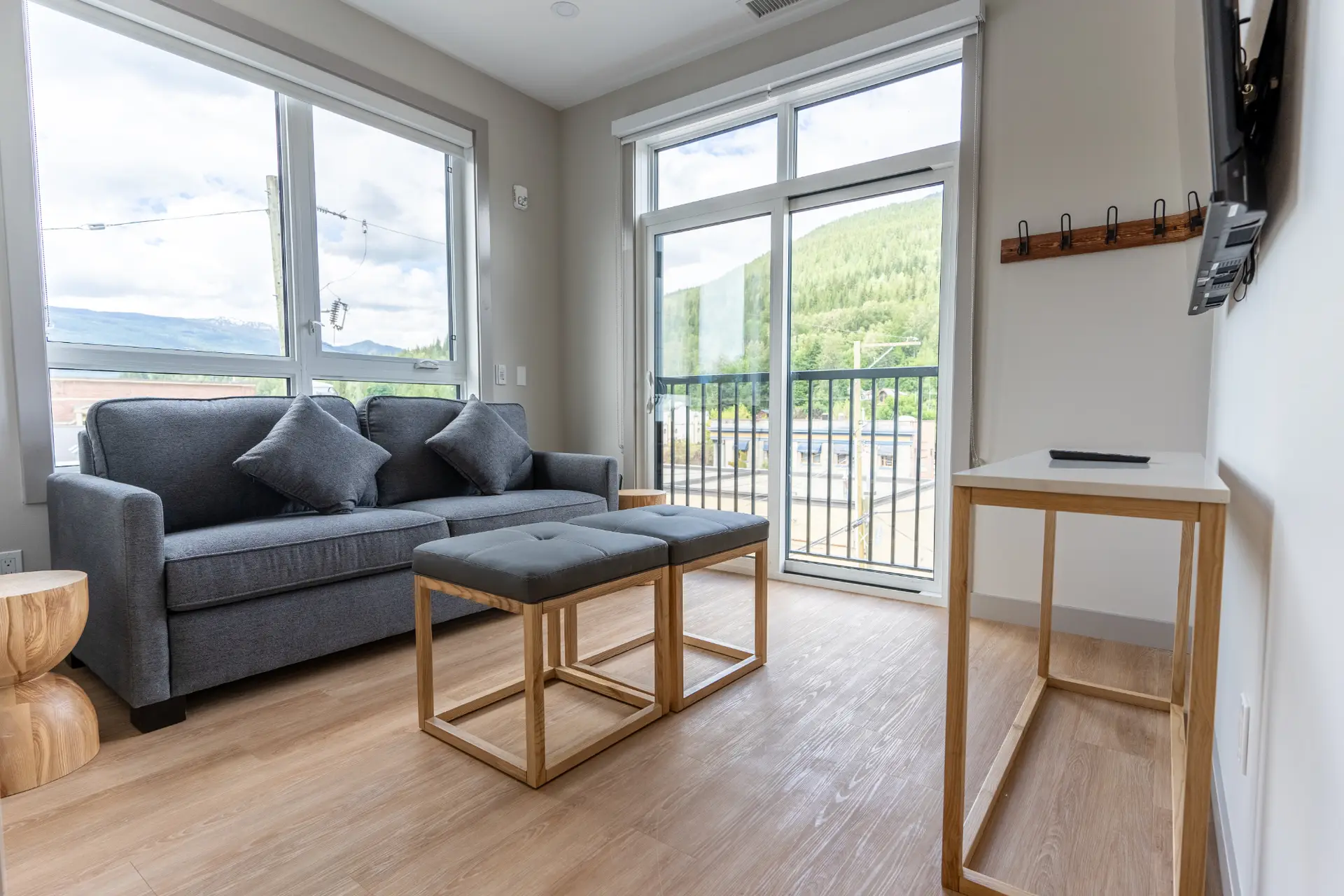 Living room of a Basecamp Suites Revelstoke two-bedroom suite with sofa, ottomans, and mountain view