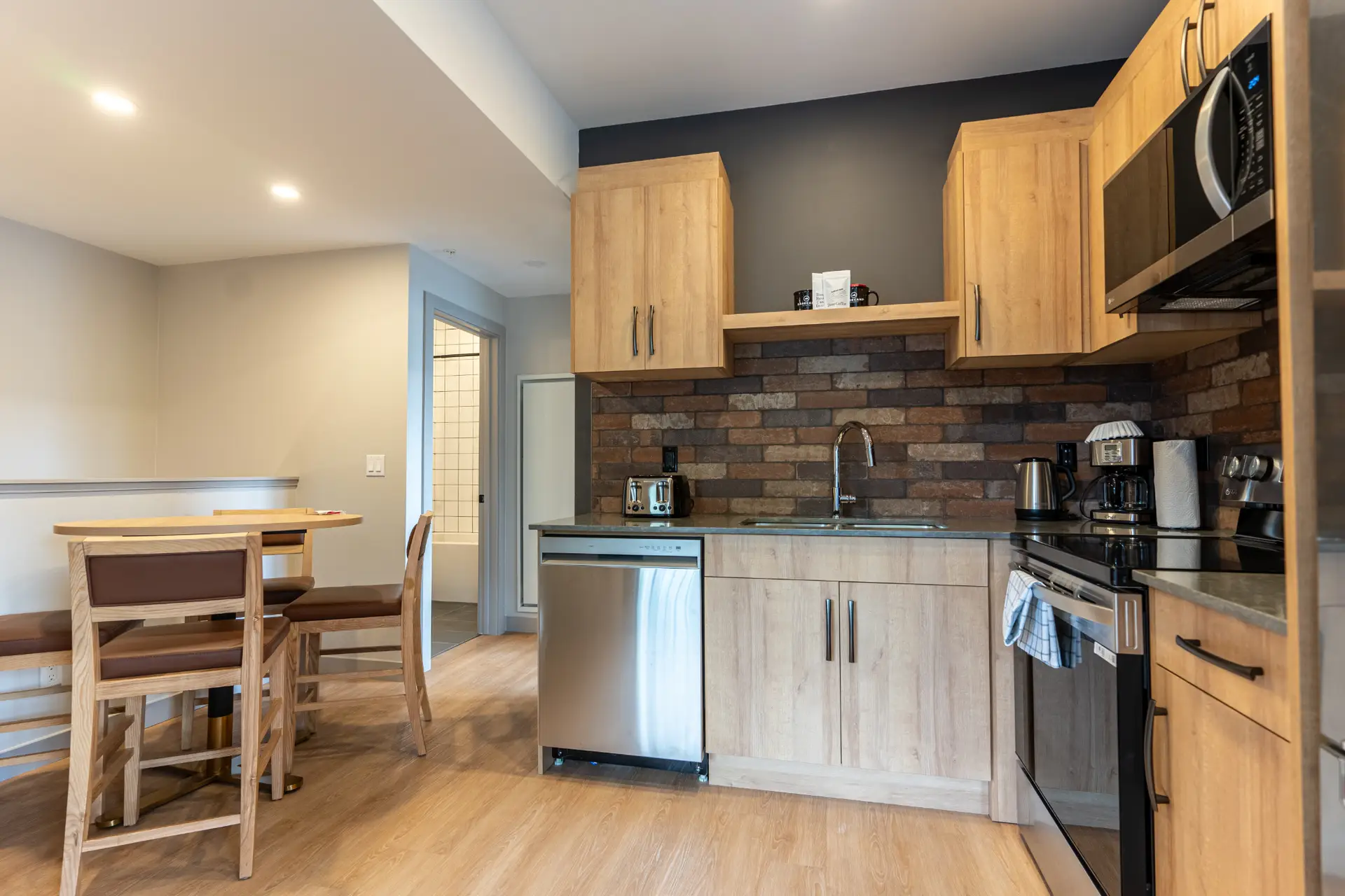 Modern kitchenette with stainless steel appliances and wood cabinetry in Basecamp Suites Revelstoke