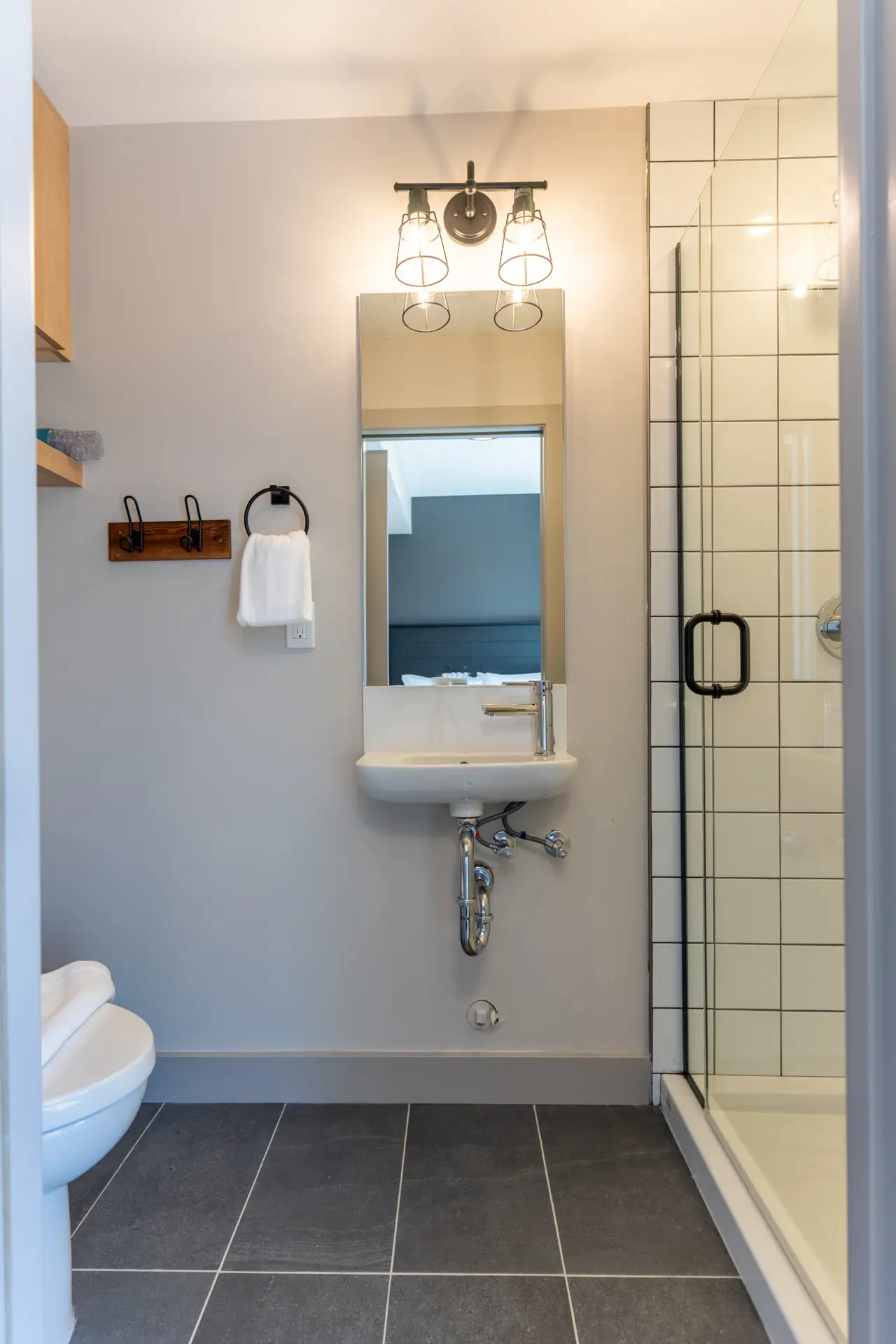 Modern bathroom with a small sink, toilet, and tiled shower in Basecamp Suites Revelstoke.