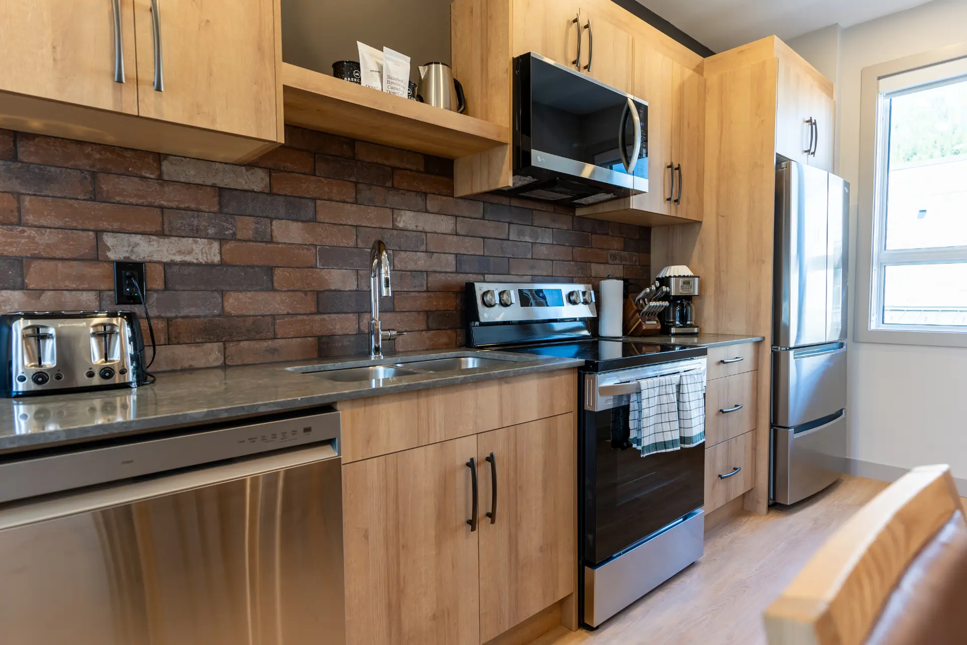 Modern kitchen in Basecamp Suites Revelstoke Two Bedroom Queen Suite with stainless steel appliances.