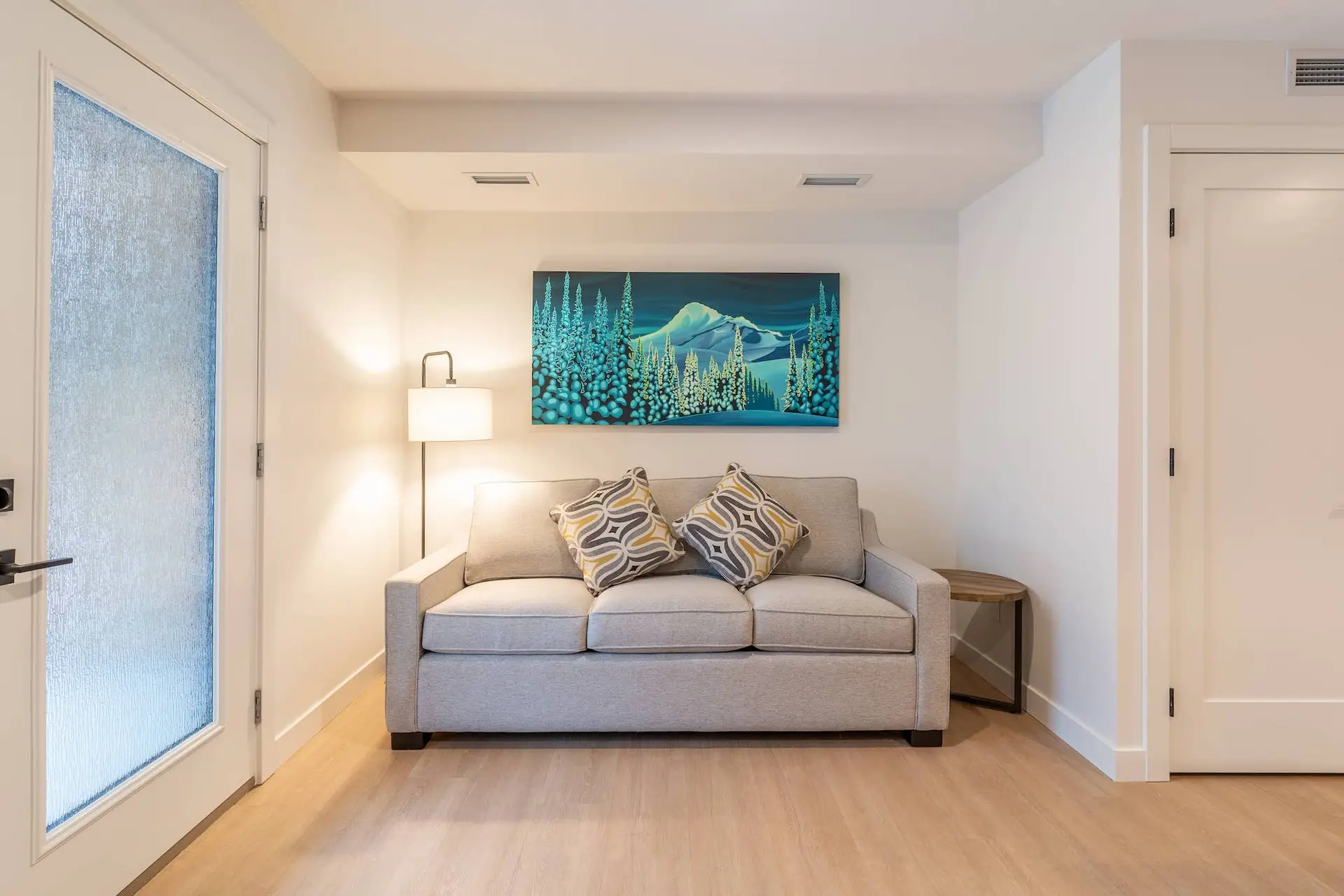 One bedroom suite living area at Basecamp Resorts Revelstoke with sofa and mountain art