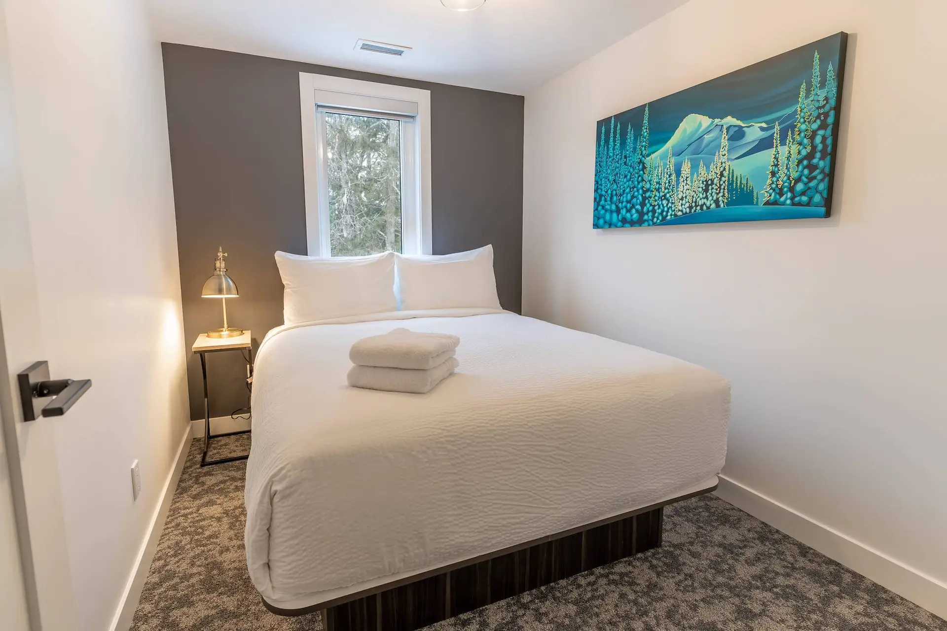 Revelstoke suite bedroom with mountain art and white linens