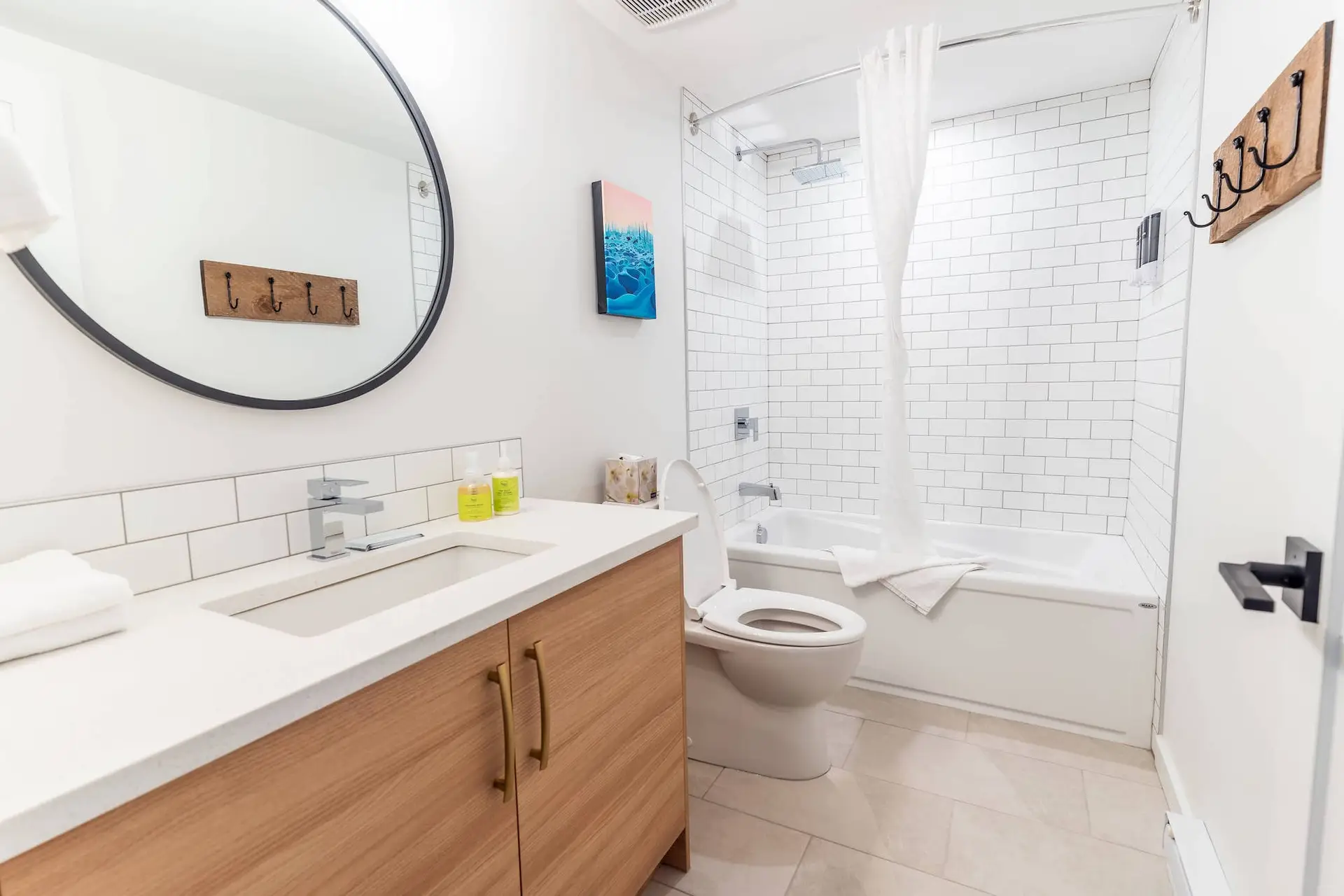 Modern bathroom with subway tile shower, wooden vanity, and white toilet in Revelstoke suite.