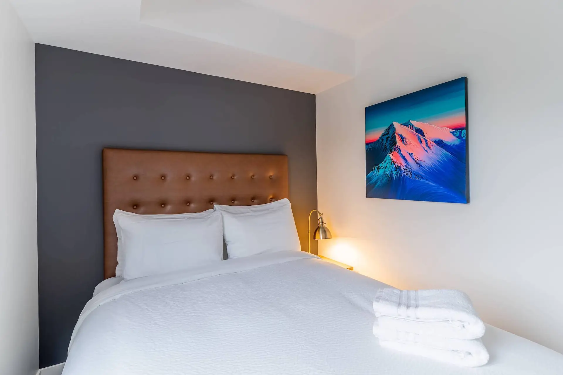 Revelstoke Four Bedroom Suite: King bed with white linens and a mountain art print.