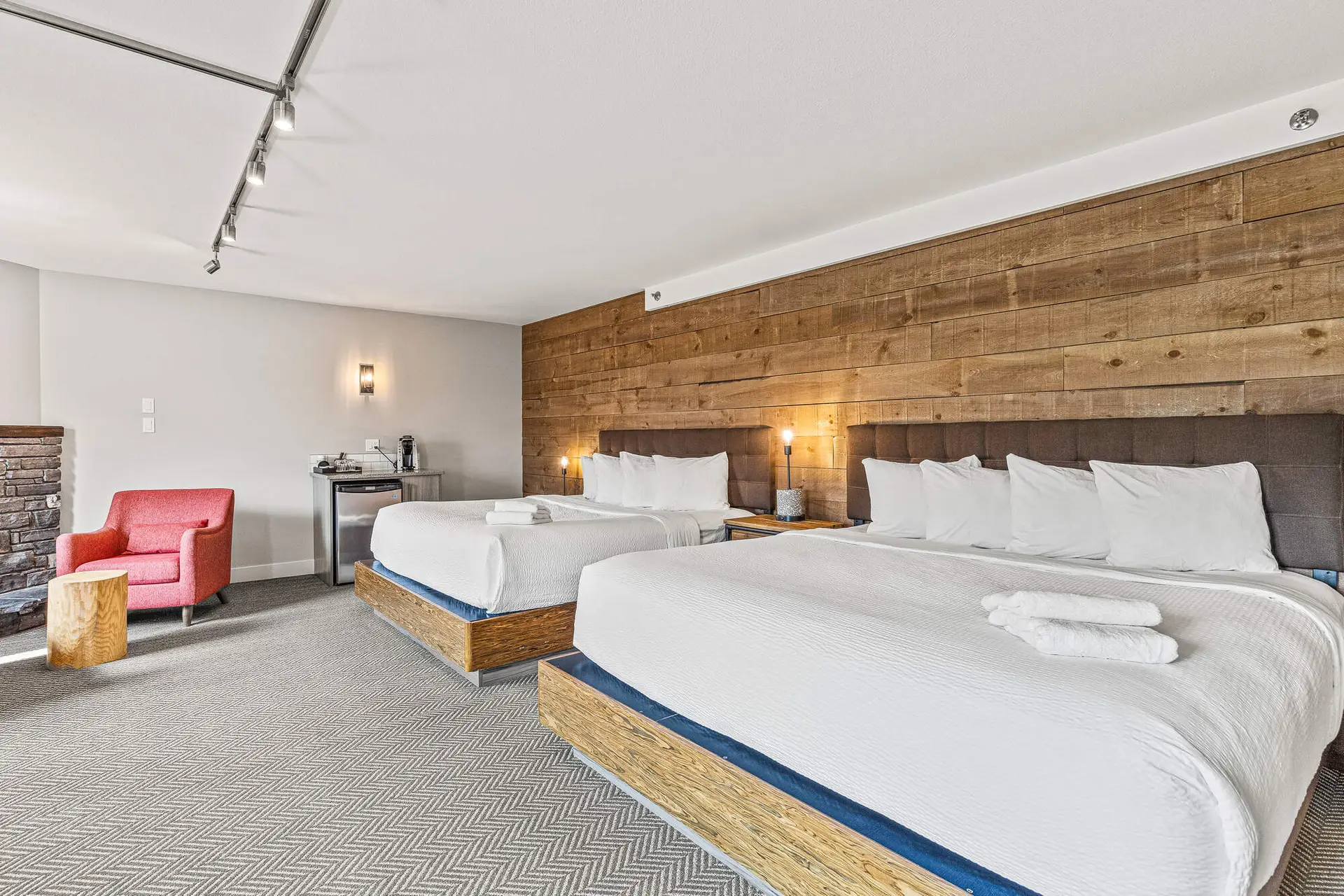 Deluxe double king room at Basecamp Lodge Canmore with wood accent wall and fireplace.