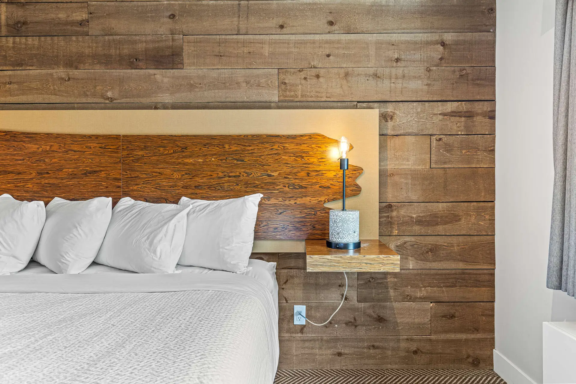 Basecamp Lodge Canmore king room: cozy bed, wood accent wall, bedside lamp.