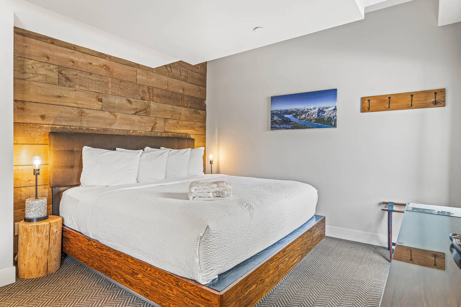 Basecamp Lodge Canmore micro suite: queen bed, wood accent wall, mountain art.