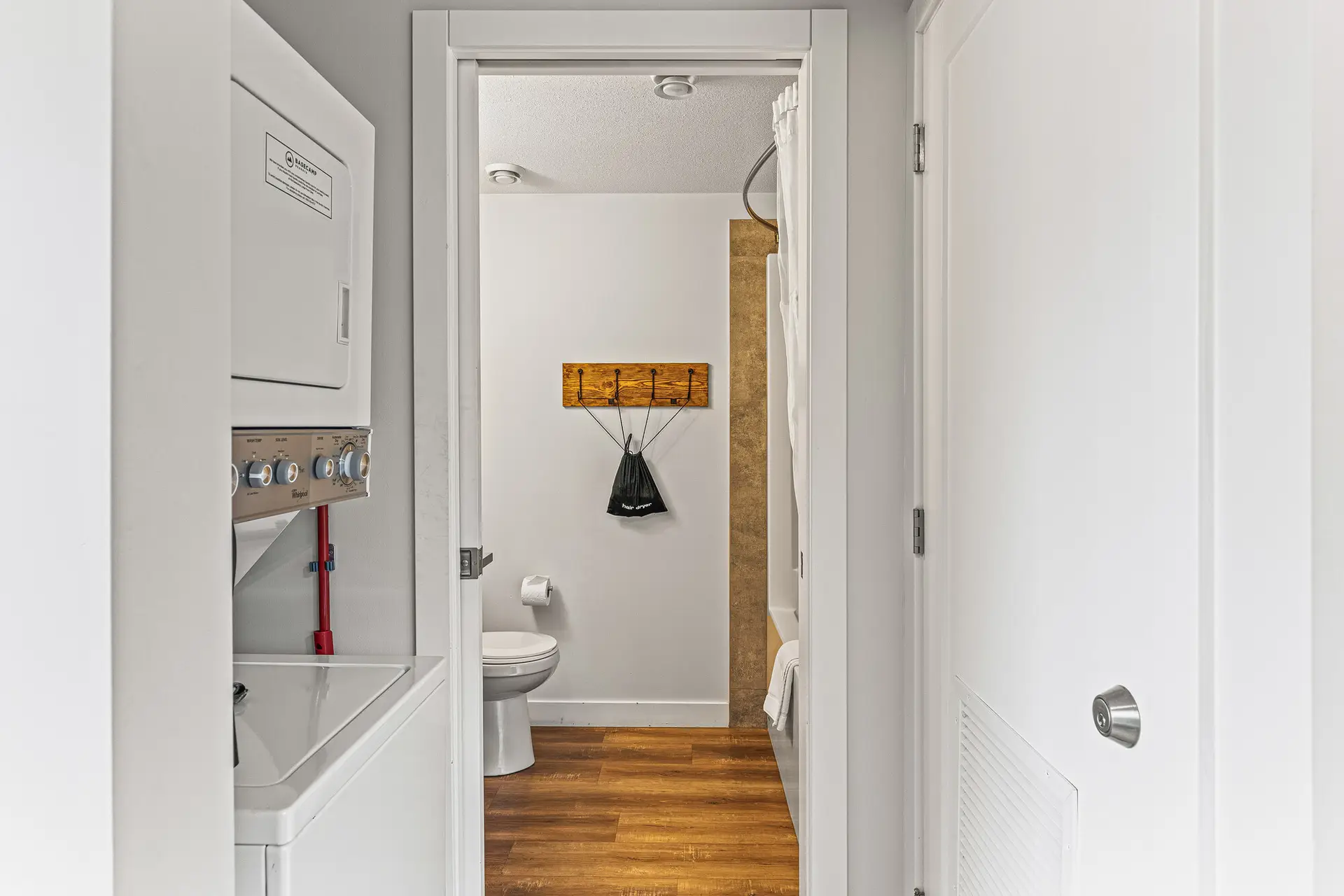 Micro studio bathroom with toilet, shower, and laundry in hallway