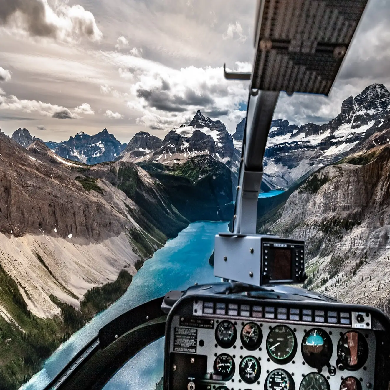 Helicopter cockpit view of turquoise lake and Canadian Rockies