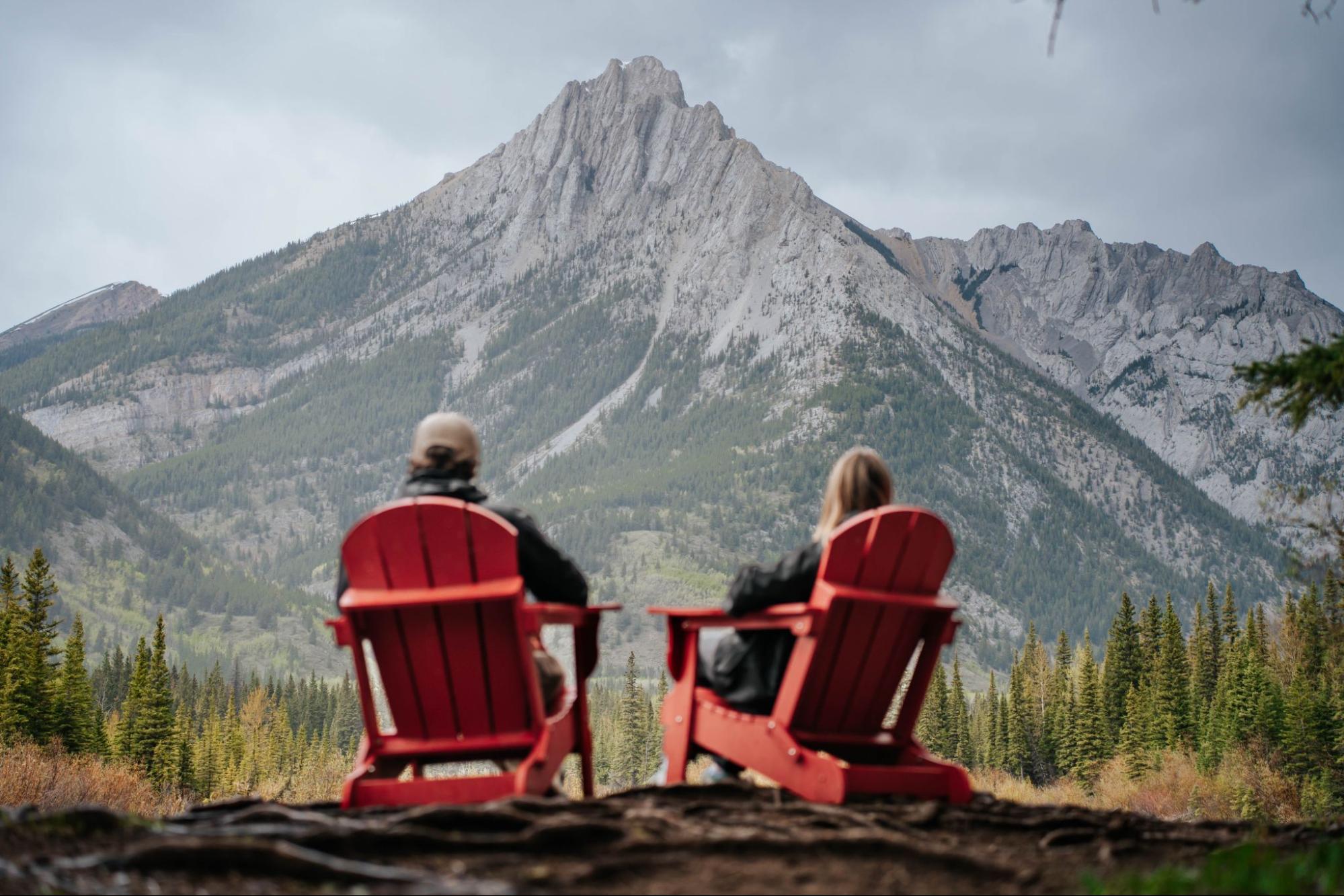 Couple relaxing in red chairs overlooking Kananaskis mountain range, best hikes Kananaskis